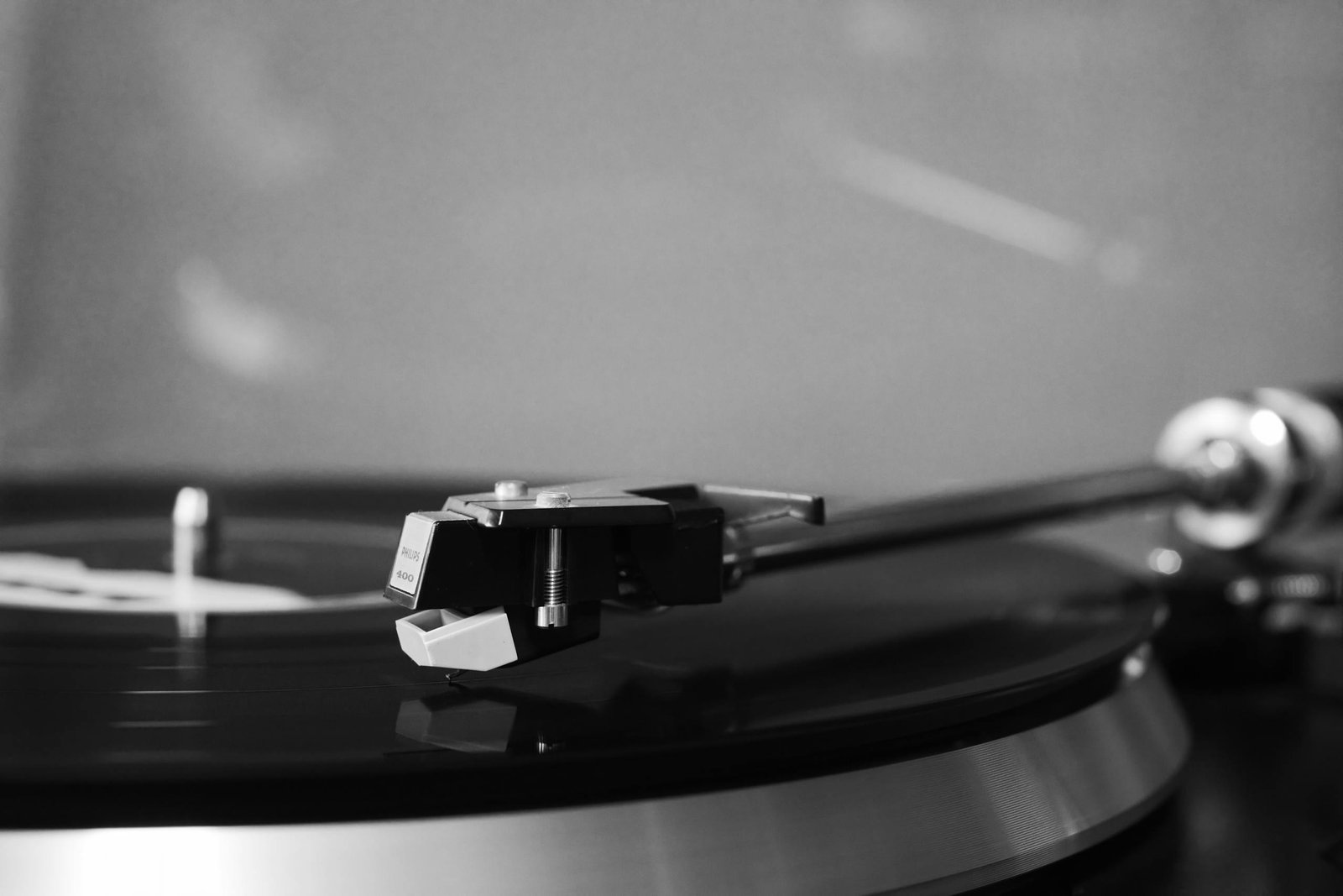 Black and white image of a vintage turntable with a vinyl record in close-up view.